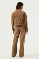 Back view of a woman wearing the Aspen cropped utility jacket in brown, featuring a cropped hem, long sleeves and structured seaming.