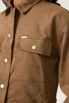 Close-up of the brown Aspen cropped utility jacket showing the collared neckline, snap-button closure and flap chest pocket.