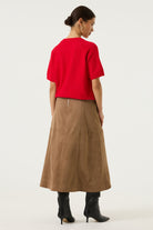 Woman wearing a brown Rosalie seamed midi skirt with a red short-sleeve knit top and black knee-high boots, shown in a full-length studio view.