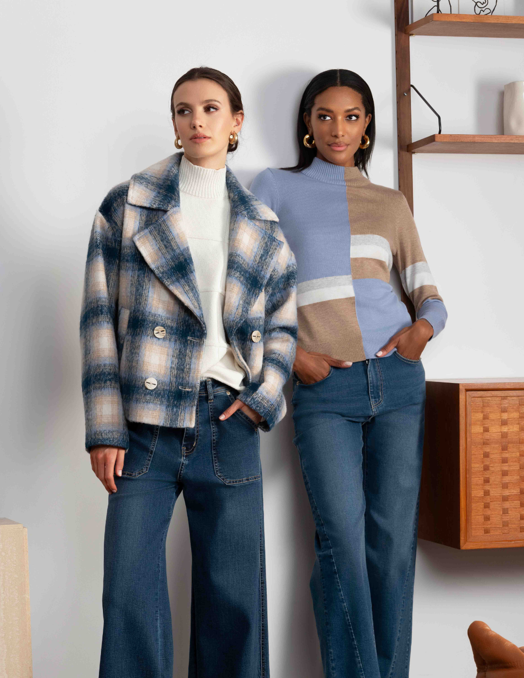 Two women standing side by side wearing matching outfits with plaid jackets and jeans.