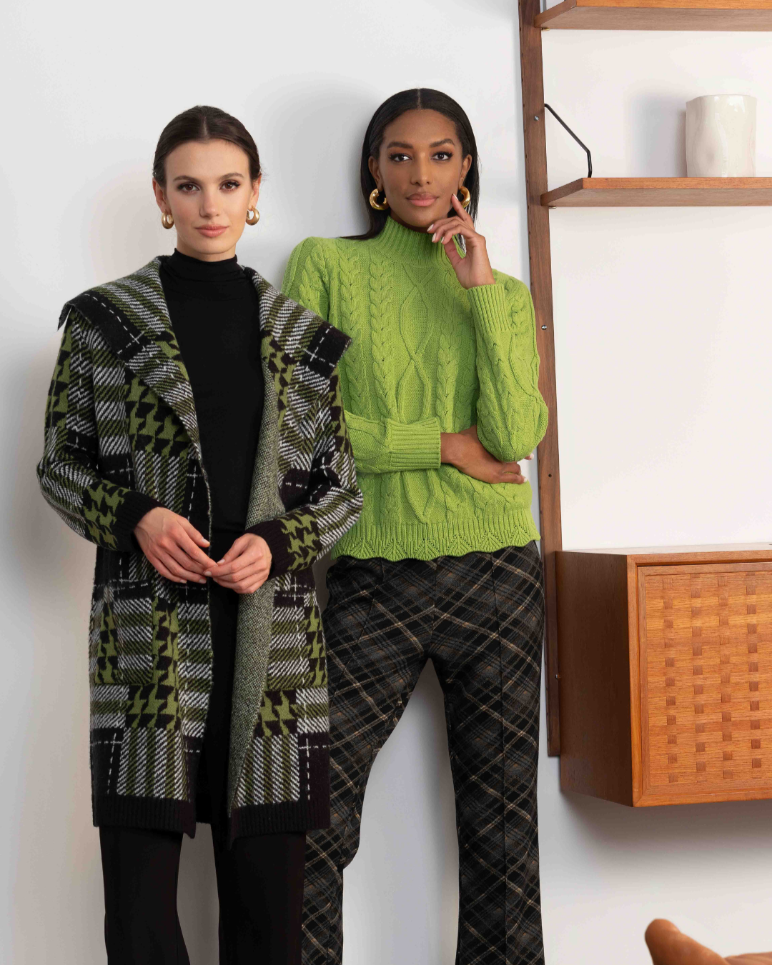 Two women wearing stylish outfits with a modern interior background