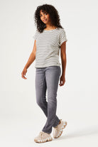 Women's black and white striped knit t-shirt featuring a relaxed silhouette, rolled short sleeves, and round neckline. Paired with grey slim-leg jeans and chunky sneakers.