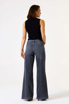 Women's ribbed mock neck sleeveless knit top shown from the back, featuring a fitted silhouette and clean finish. Styled with wide-leg denim jeans to showcase the top's versatile everyday appeal.