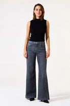 Women's ribbed mock neck sleeveless knit top with a flattering fitted shape and streamlined silhouette. Paired with wide-leg jeans for a polished casual look suitable for work, weekends, or layering.