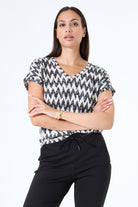 Women's black and white zigzag print V-neck tee with short sleeves, shown from the front and paired with black drawstring pants.