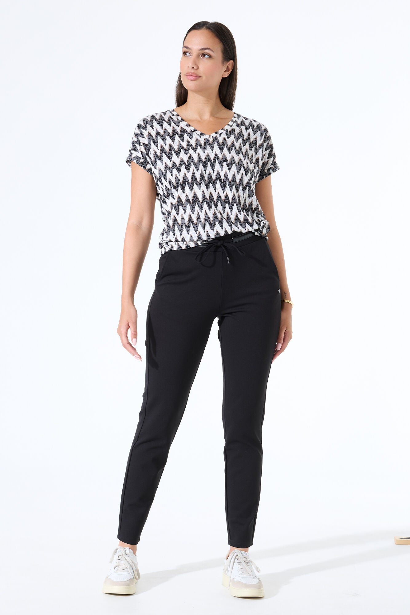 Women's black and white zigzag print V-neck tee with short sleeves, shown from the front and paired with black drawstring pants.