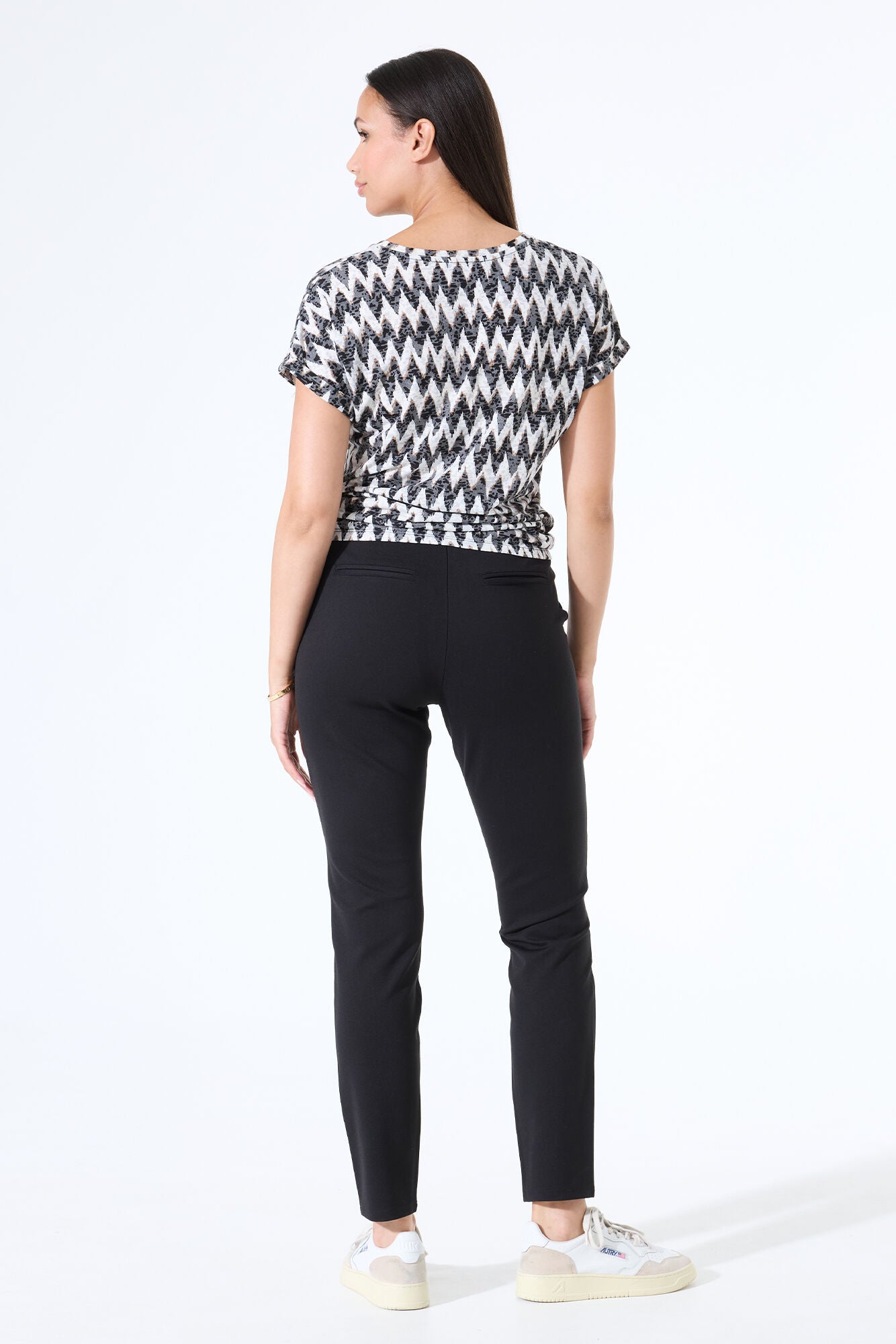 Women's black and white zigzag print short-sleeve tee shown from the back, featuring a relaxed fit and lightweight drape, paired with black pants.