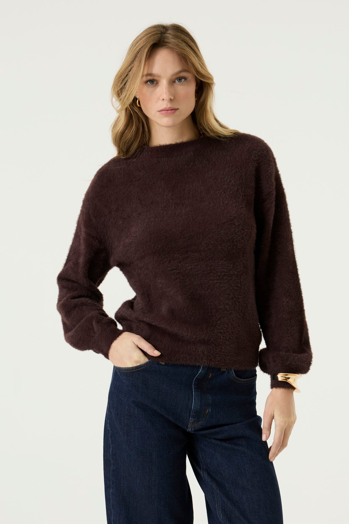 Model wearing the Alora Soft Texture Sweater in rich brown, featuring a relaxed silhouette, soft textured knit, and long sleeves, paired with dark wash jeans.