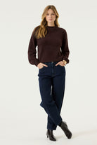 Model wearing the Alora Soft Texture Sweater in rich brown, featuring a relaxed silhouette, soft textured knit, and long sleeves, paired with dark wash jeans.