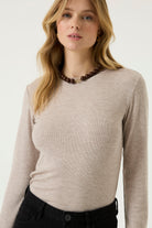 Woman wearing a beige ribbed long-sleeve tee with a crew neckline and fitted silhouette.