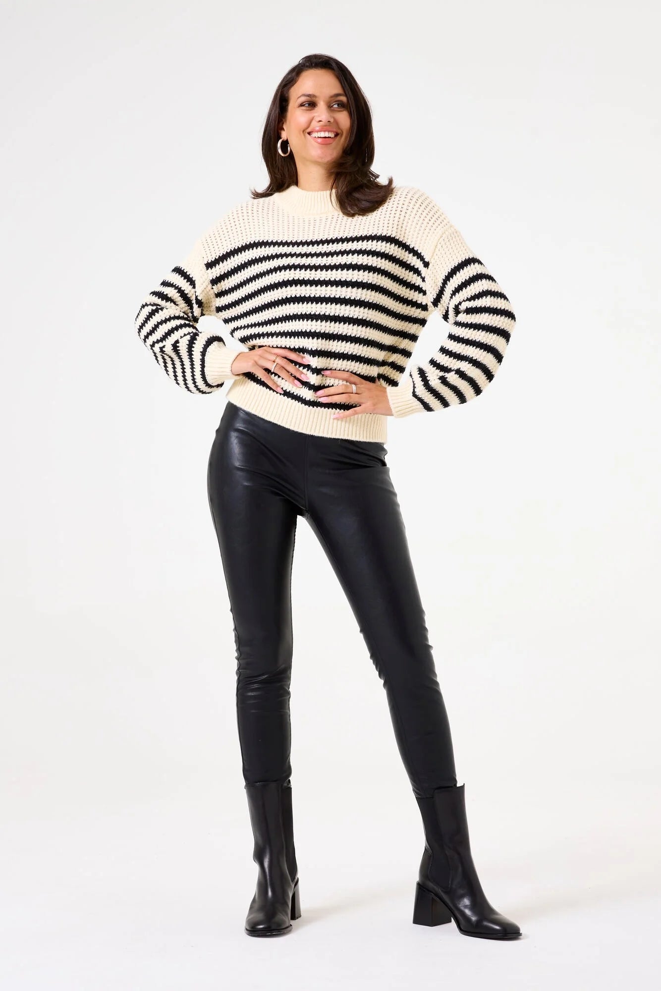 Stylish model in striped sweater paired with City Edge vegan leather legging and ankle boots.