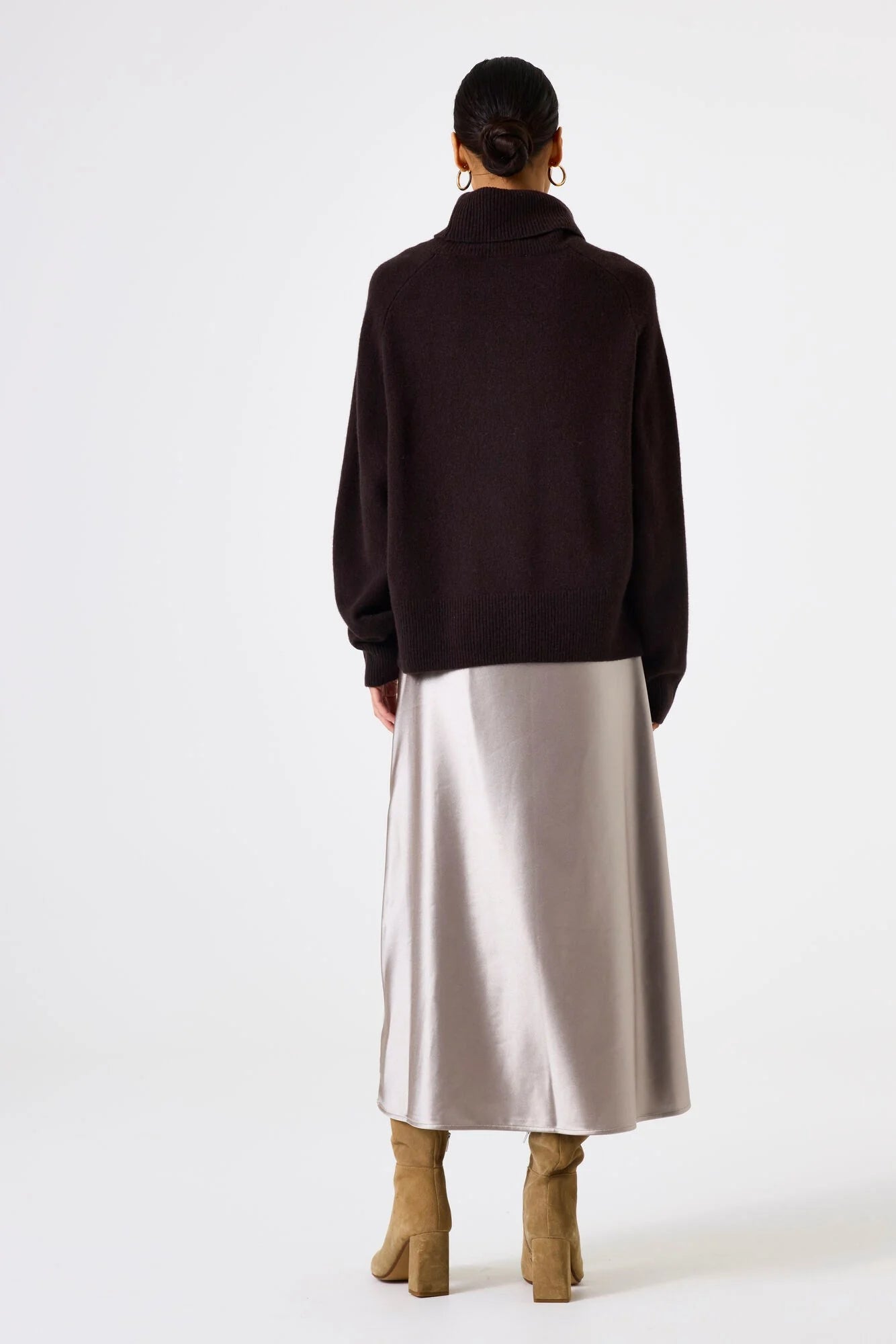Person wearing a dark sweater and light-colored skirt on a white background