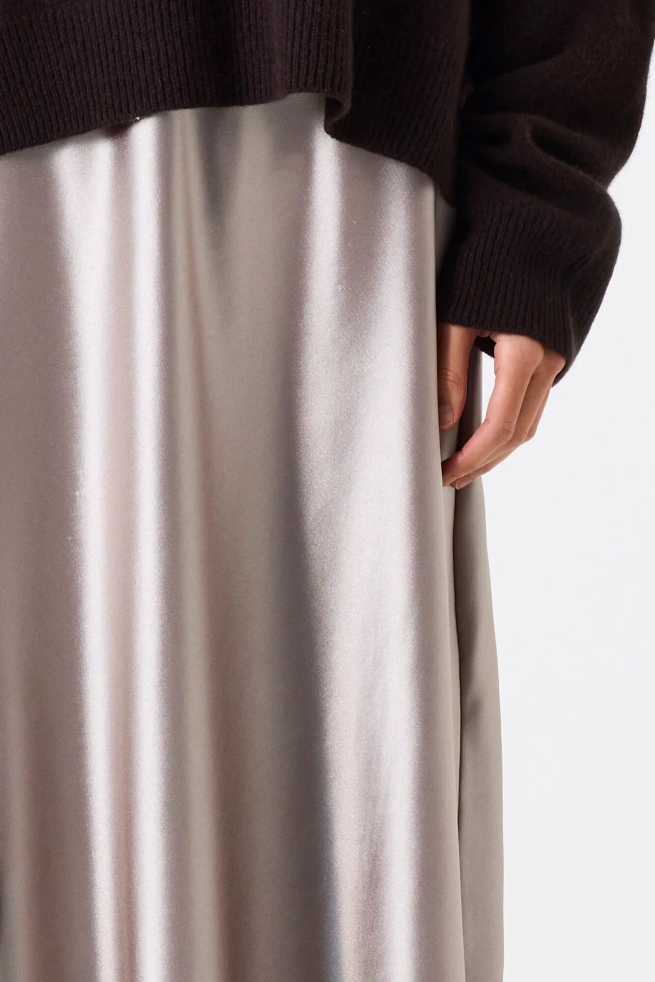 Close-up of a person wearing a dark sweater and light-colored skirt on a white background