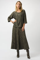 fashionable woman standing wearing a deep-green coloured top and skirt