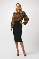 blonde woman standing in a leopard-print top and black pencil skirt