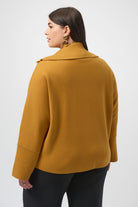 woman standing in mustard yellow sweater with her back facing us