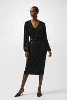 woman standing in fashionable black long-sleeve top with beaded pattern on sleeves