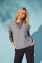 Woman wearing a gray sweater with black sleeves against a light blue background